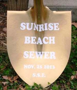 gold shovel with words Sunrise Beach sewer on it