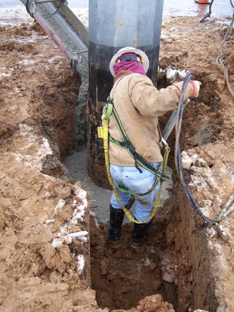 man in trench pouring concrete